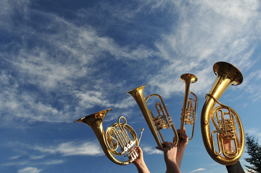 4 Blechblasinstrumente werden gen Himmel gestreckt. Mit dabei: Horn, Flügelhorn, Trompete und Bariton.