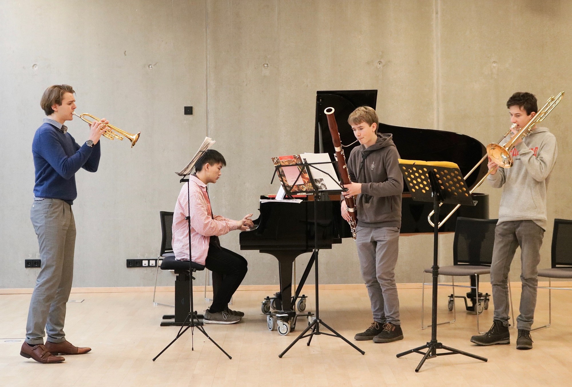 4 junge Menschen musizieren auf unterschiedlichen Instrumenten (Klavier, Trompete, Fagott und Posaune) zusammen.